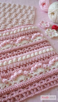 a crocheted blanket is laying on the table next to some yarn and scissors