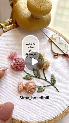 someone is stitching flowers on a wooden hoop with needle and thread in front of it