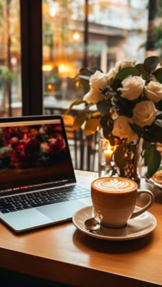 a laptop computer sitting on top of a wooden table next to a cup of coffee