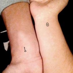 two people with matching tattoos on their arms, one is holding the other's arm