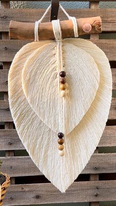 a white heart hanging on a wooden wall with beads and wood bead necklaces