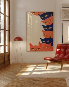 a red chair sitting in front of a window next to a painting on the wall