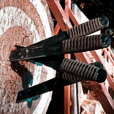 two pairs of scissors are stuck into the side of a wooden target on a fence