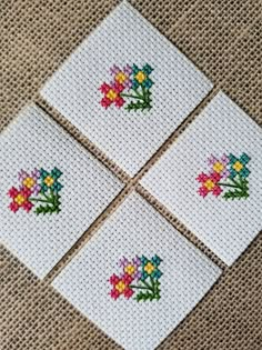 four cross stitch coasters with flowers on them