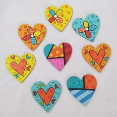 six heart shaped magnets with different designs on them, all painted in bright colors