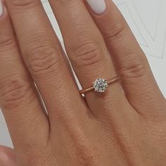 a woman's hand with a diamond ring on top of her finger and the other hand holding an engagement ring