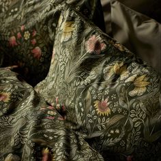 a close up view of the fabric on a bed with flowers and leaves in it