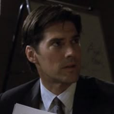 a man in a suit and tie holding a piece of paper with writing on it