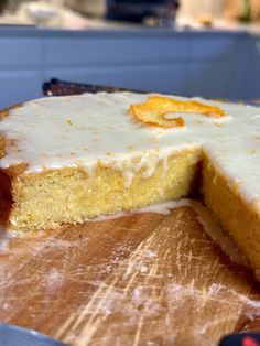 a cake with white frosting and orange slices cut out on a wooden cutting board