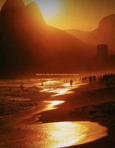 people are walking on the beach as the sun goes down in the distance with mountains in the background