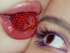 a close up of a woman's lips with a raspberry on her lip