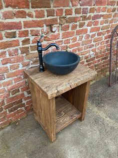 an outdoor sink in front of a brick wall with a black faucet on it