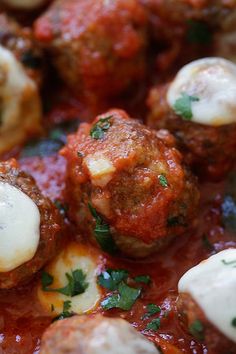 meatballs covered in marinara sauce and cheese with parsley sprinkled on top