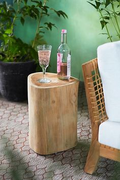 a wooden table with two wine glasses on it next to a chair and potted plant