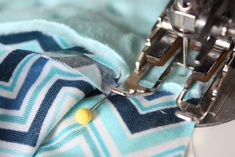 the sewing machine is working on the blue and white fabric that has been sewn