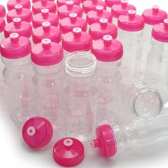 many plastic bottles with pink caps are arranged in a circle on a white surface,