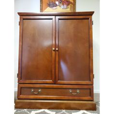 a wooden armoire sitting on top of a carpeted floor next to a painting