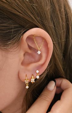 a close up of a person wearing an ear cuff with two small stars on it