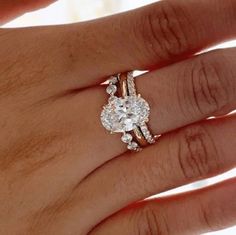 a woman's hand with two rings on it and an engagement ring in the middle