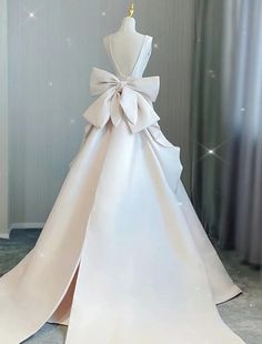 a white wedding dress with a big bow on the front and back, is displayed