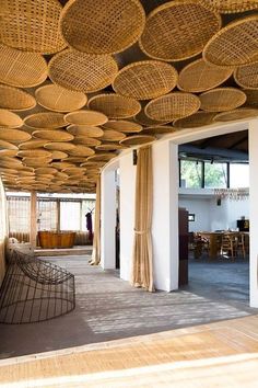 the interior of a restaurant with wicker baskets hanging from the ceiling and chairs on the floor