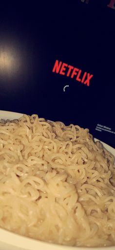 a bowl of noodles sitting on top of a table next to a television remote control