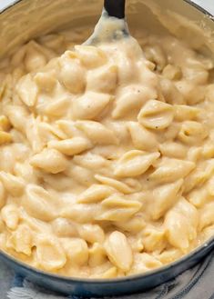 macaroni and cheese is being stirred with a spoon in a blue pot on the stove