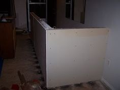 an unfinished room with a refrigerator in the middle