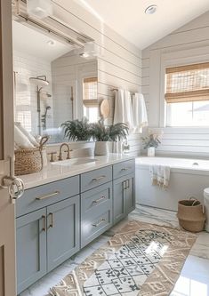 a bathroom with blue cabinets, white walls and a rug on the floor in front of the bathtub