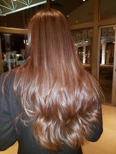 the back of a woman's head with long, brown hair in front of an elevator