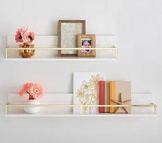 two white shelves with flowers, books and pictures on them next to a vase filled with pink flowers