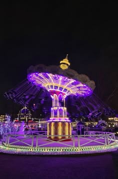 an illuminated carousel at night with purple lights