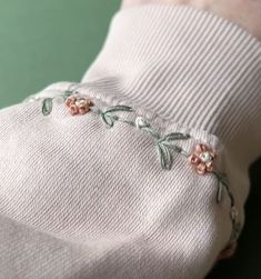 a white sweater with pink flowers embroidered on it