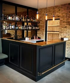 an empty bar with bottles on the shelves and chairs around it in front of a brick wall