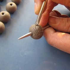 a person is making beads with some metal tips and wood beads on the table in front of them