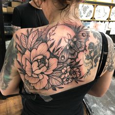 a woman's back with flowers and birds tattoo on her upper half - arm