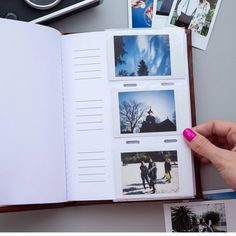 an open book with pictures and photos on the pages is being held by a woman's hand