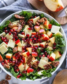 a white bowl filled with apples, cheese and pomegranate on top of a table