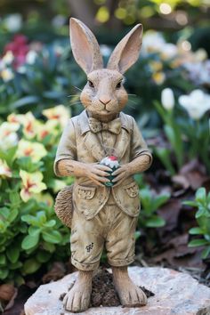 a statue of a rabbit holding a ball in its hands and standing on a rock