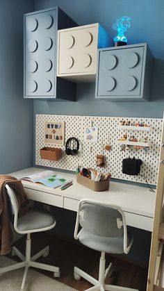 a white desk topped with a laptop computer next to a wall mounted legos on it