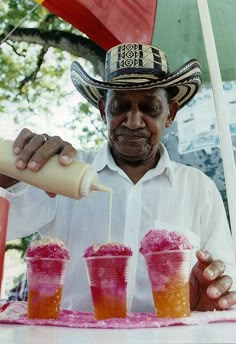 a man pouring drinks into cups with straws