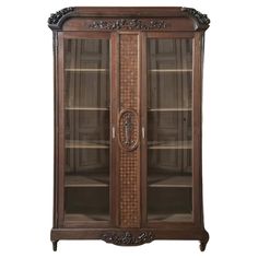 an antique display cabinet with glass doors and carvings on the front, in dark wood