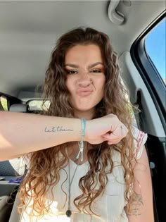 a woman sticking her tongue out in the back seat of a car, with tattoos on her arm