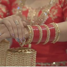 two women in red dresses holding gold bracelets and wearing matching rings on their hands