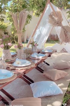 a table set up with plates and napkins for an outdoor dinner party in the shade