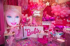 there is a barbie doll on display in the room with balloons and confetti