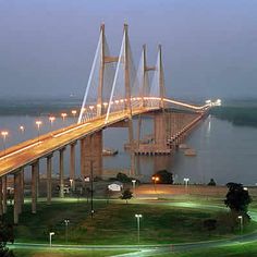 a large bridge spanning over a body of water with lights shining on the side of it