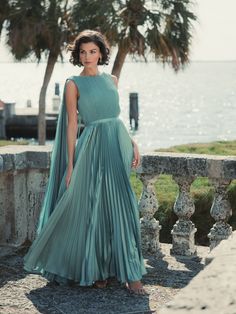 a woman in a green dress standing by the water