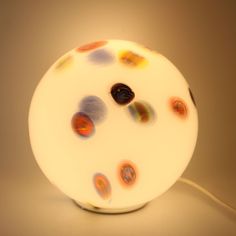 a white lamp with multicolored circles on it's side and a cord plugged in