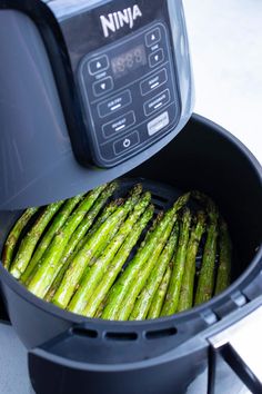 asparagus being cooked in an air fryer with the lid open to show it's freshness